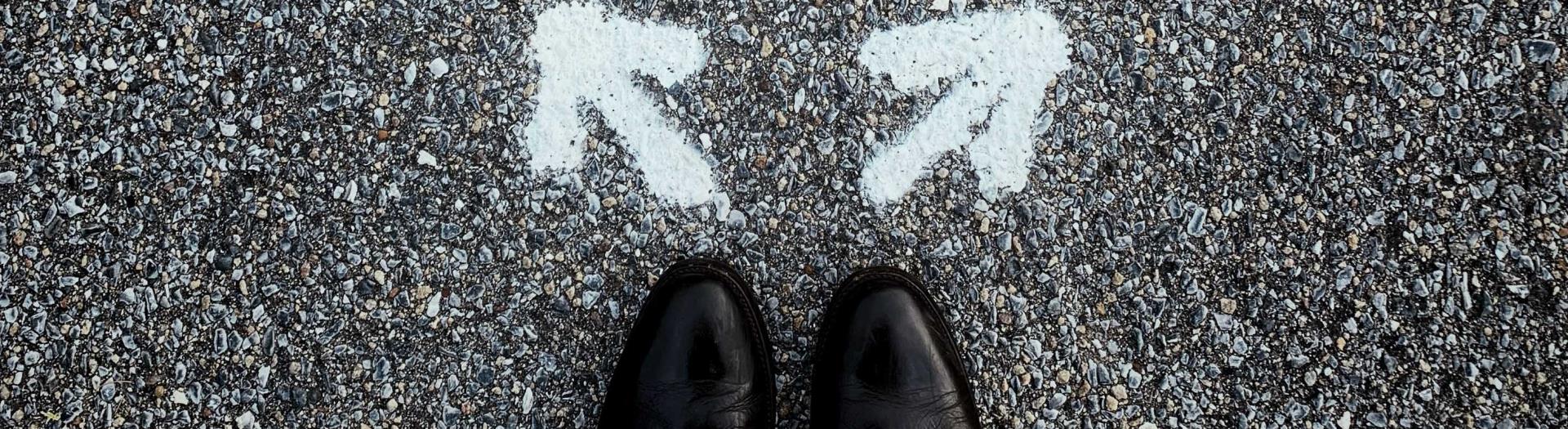Shoes standing in front of two arrows pointing different directions