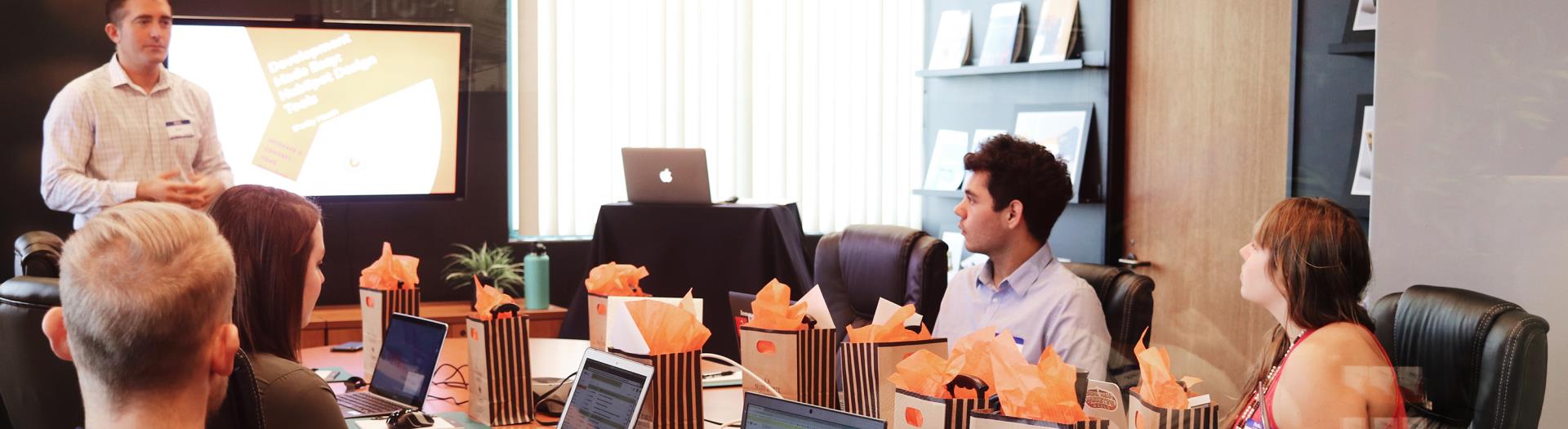 a team of professionals around a table listening to someone speak