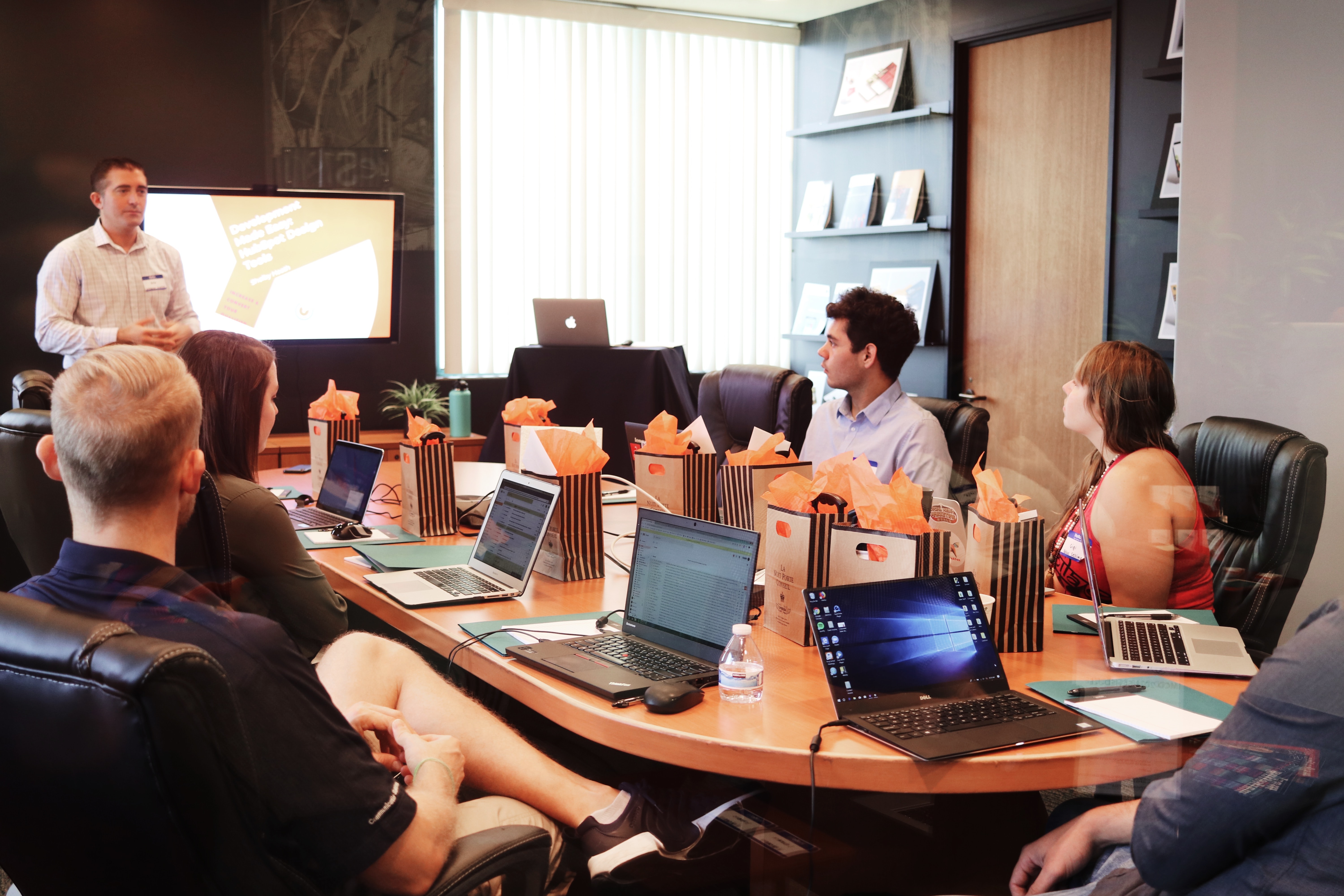 people around a conference table listening to someone present at a screen